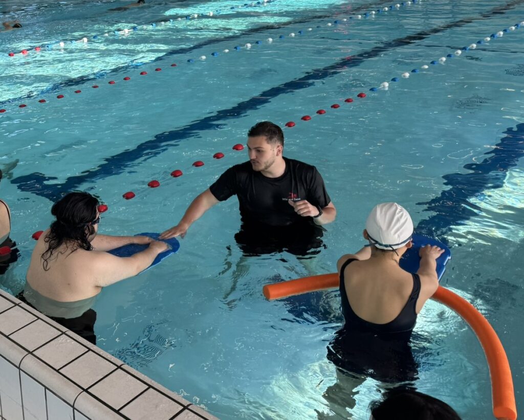 Aquaphobia Swimming lessons 1 Swimming coach David helping 2 beginners to kick with the legs in the Noord Amsterdam swimming pool