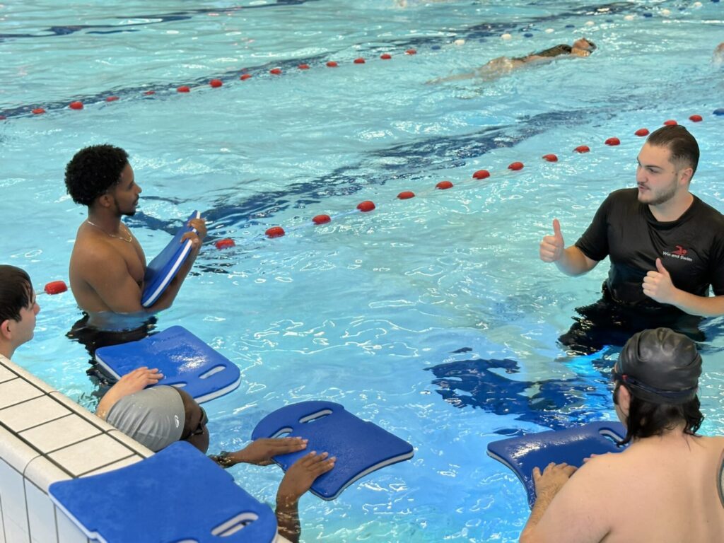 Home 15 Swimmers resting at the wall while discussing freestyle technique with the coach David